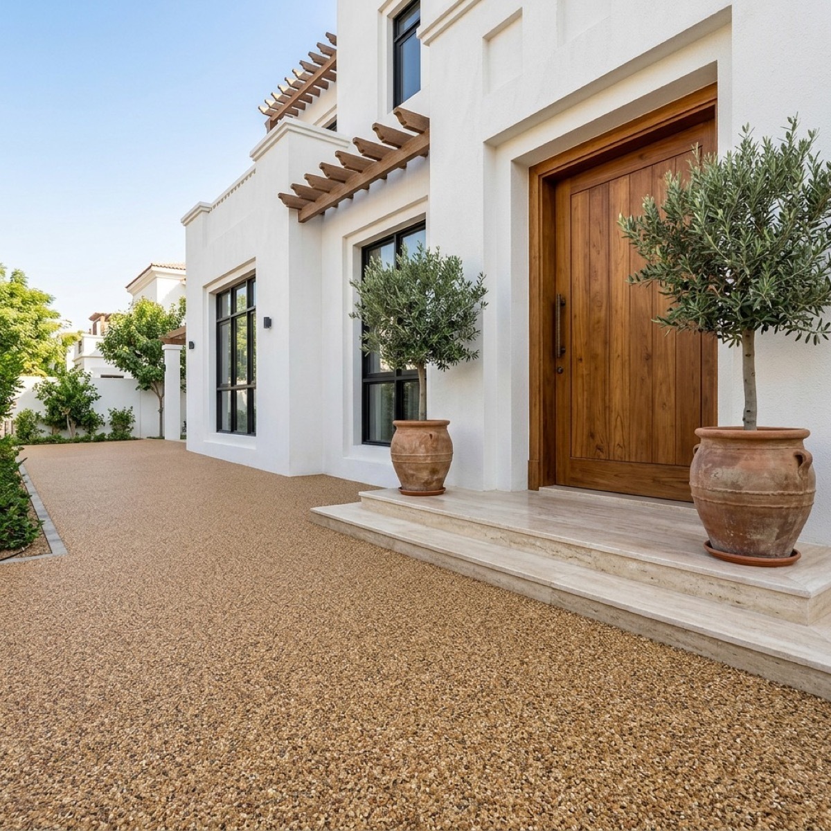 Resin bound path to a villa entrance with a potted olive tree